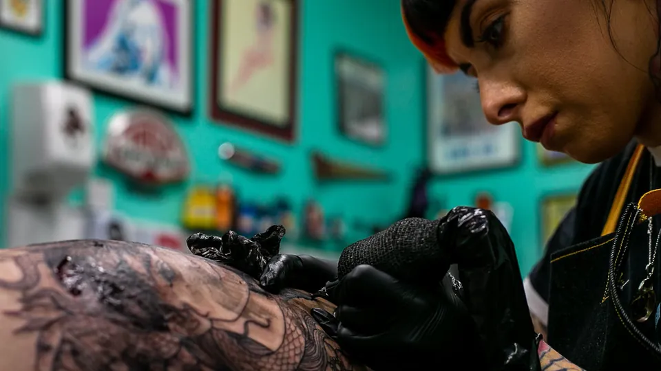 Tätowiererin arbeitet in ihrem Studio an einem Tattoo